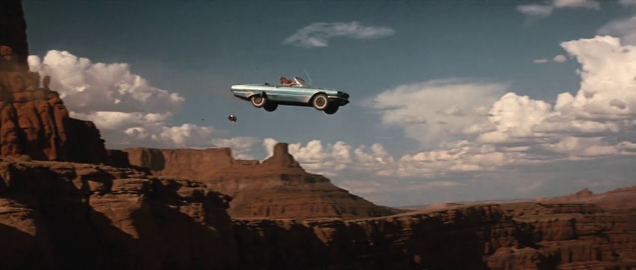 A blue car flying off a cliff into the Grand Canyon. Still image from the film Thelma and Louise