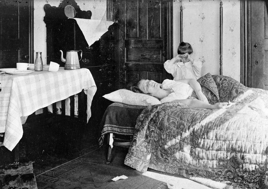 A girl stands next to her sister, who is lying in bed, in November of 1918. The young girl became so worried that she telepho